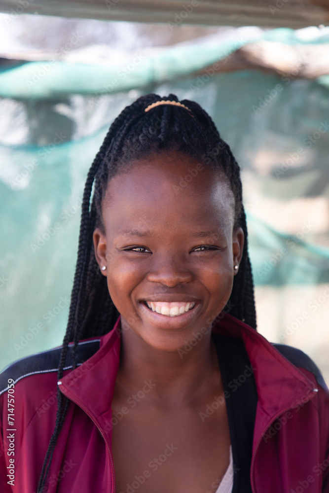 Naklejka premium village smiling african social worker young woman with braids standing in the yard