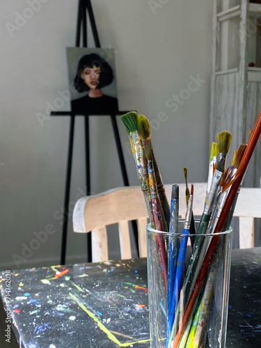 An art workshop with a palette of colorful paints, brushes in a glass