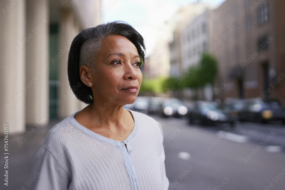Fototapeta premium older woman in city street, sad thoughtful expression