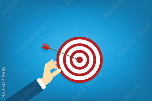 Hand holding a target, showing a goal. Red arrow hits the center. Business challenge failure and success concept.	