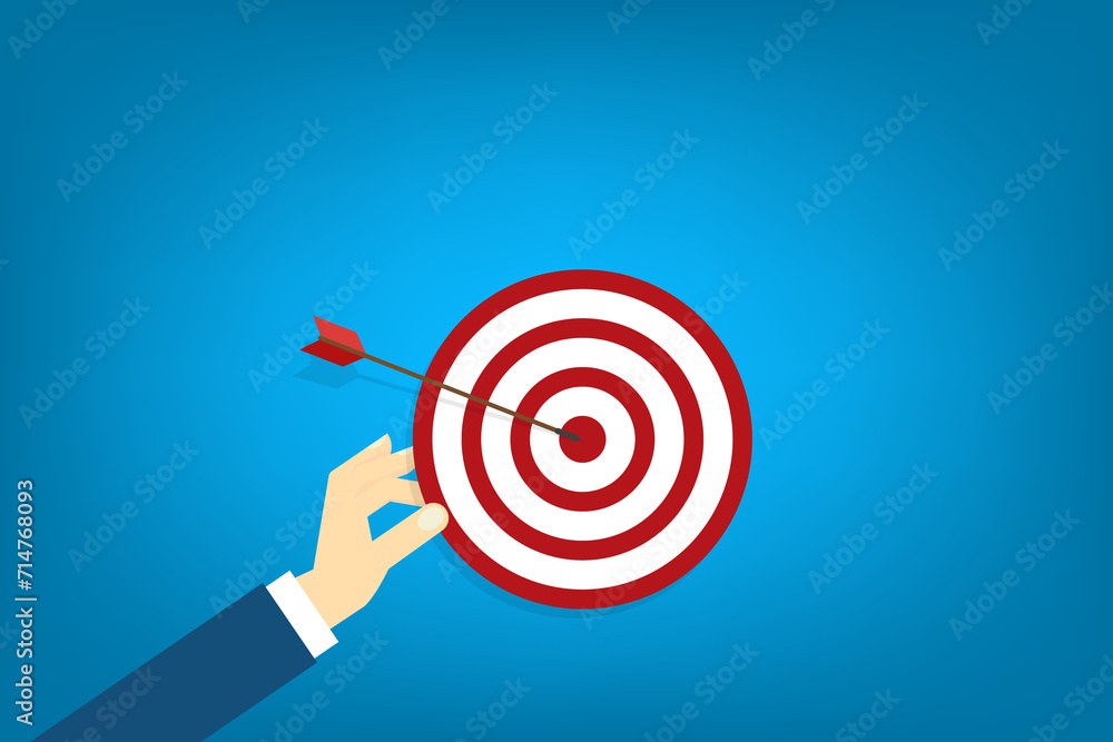 Hand holding a target, showing a goal. Red arrow hits the center. Business challenge failure and success concept. Hand holding a target, showing a goal. Red arrow hits the center. Business challenge failure and success concept.