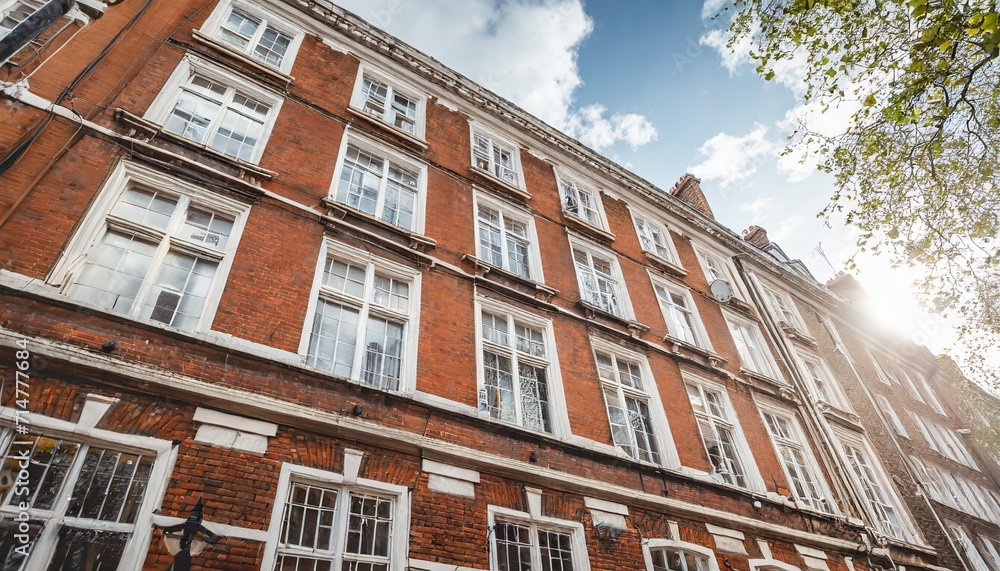 classic historical apartments building in georgian british english style with white windows and red brick wall in central london