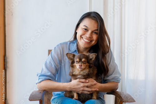 Young woman have a break at work for making selfie with her domestic pet. Young Woman Using Smartphone With Her Dog At Home.