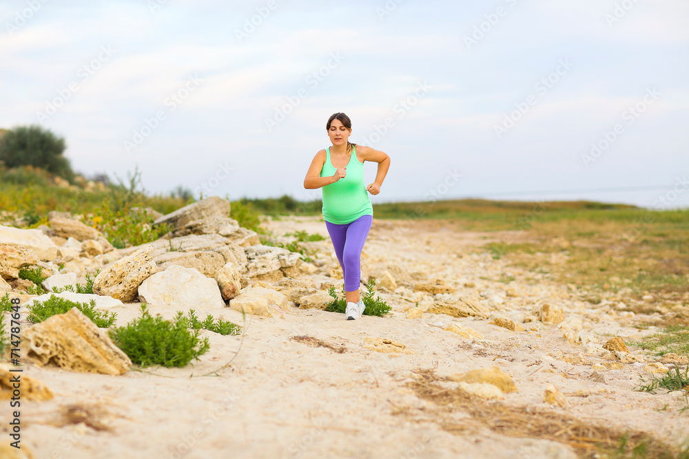 Beautiful pregnant woman doing sport in summer evening