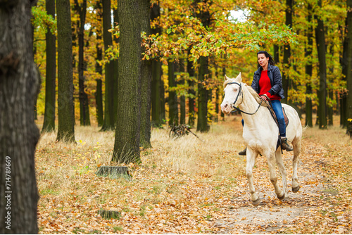 A pretty young woman and a white horse galloping through the woods © michal