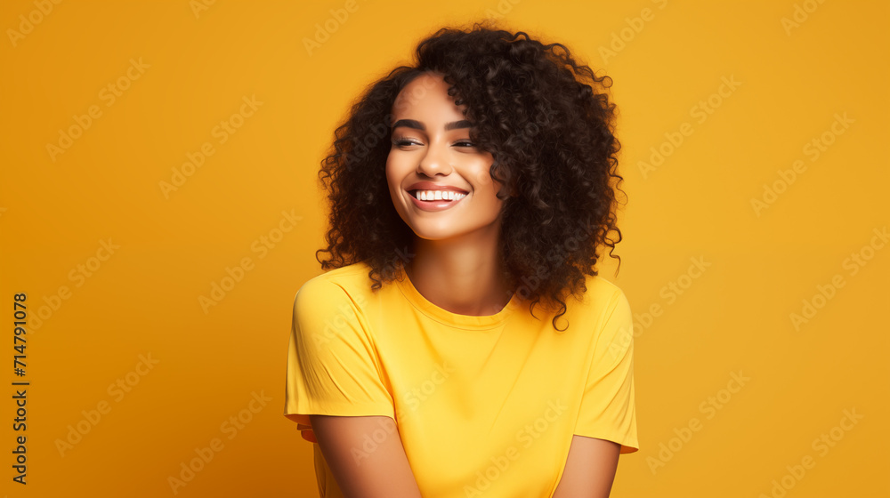 Portret studyjny młodej kobiety uśmiechniętej na żółtym tle z dużą ilością wolnego tła - obrazy, fototapety, plakaty 