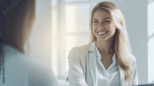 Bella donna con capelli biondi e camicia bianca sorride in ufficio photo