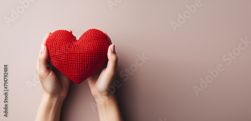 Heart in female hands. Banner or background for the holiday Valentine's Day. A woman holds a heart knitted from threads.