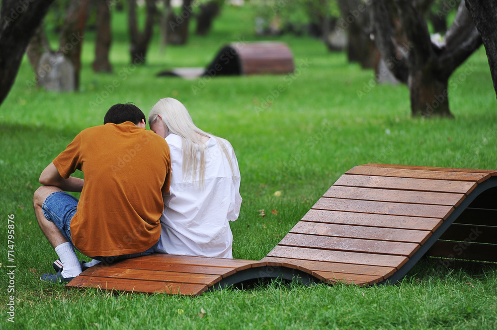 Fototapeta premium a young couple is sitting on a bench in a green garden