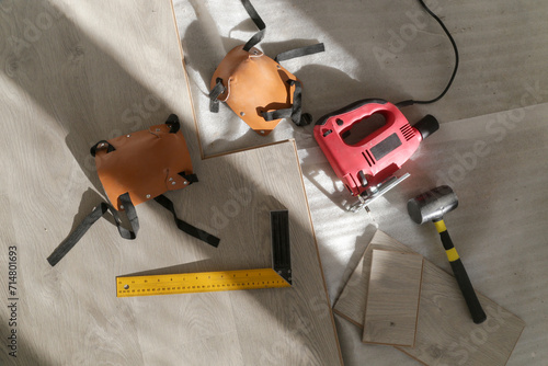 Rubber hammer, ruler with angle bar, tape meter, jig saw and other tools for installation of laminate vinyl floor. Home improvement, new floor installation.	 photo