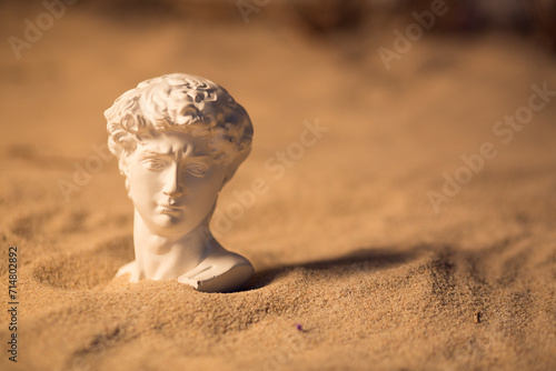 Bust of a man made of plaster, sculpture in the sand.