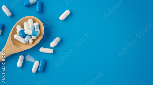 Colher de madeira com pílulas azuis e brancas isolado no fundo azul  photo