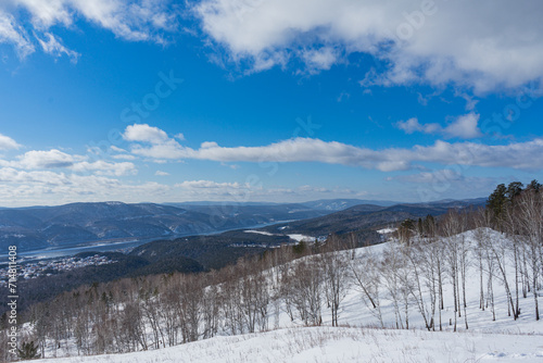 Siberian nature near Krasnoyarsk city, Russia. Yenisei river, hills and trees. Winter natural landscape, sunny day, blue sky with clouds. Gremyachaya Griva Park. Hiking trails outdoor photo