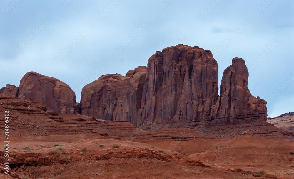 Desert landscape with red rocks and dry vegetation on red sands in Monument Valley, Navajo Nation,  Arizona - Utah