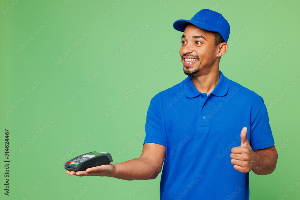 Delivery guy employee man wears blue cap t-shirt uniform workwear work as dealer courier hold bank payment terminal process credit card show like isolated on plain green background. Service concept. Delivery guy employee man wears blue cap t-shirt uniform workwear work as dealer courier hold bank payment terminal process credit card show like isolated on plain green background. Service concept.