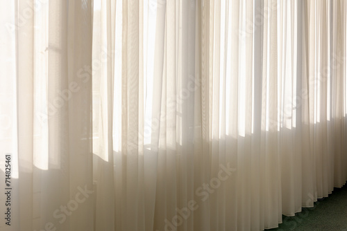 Light and see through concept  Classic white sheer curtains hanging by the window in the corridor with soft sunlight in the morning as backdrop  Fabric and linen background.