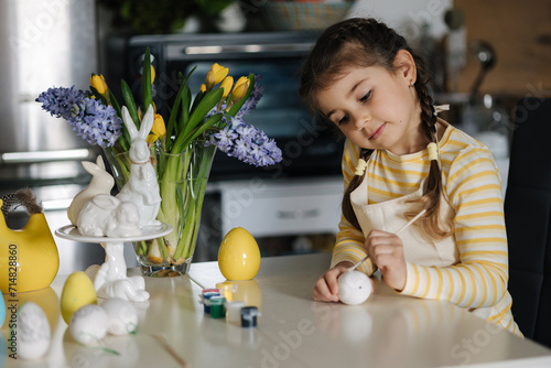 Photography Adorable little girl painting eggs on kitchen at home