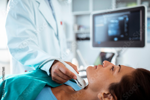 Doctor performing thyroid ultrasound examination on female patient