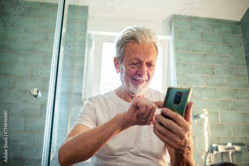 Smiling senior man using smartphone in the bathroom © Vorda Berge