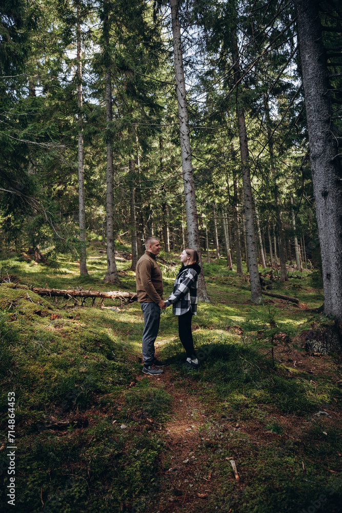 Fototapeta premium family young couple in the mountains, autumn forest. a man and a woman went to the mountains. clothes and shoes for trekking. Man and a woman went on a mountain trip. CARPATHIAN MOUNTAINS