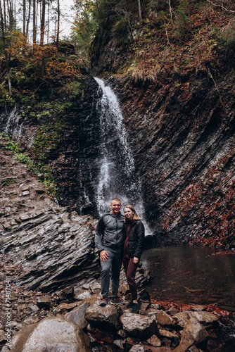 family young couple in the mountains, autumn forest. a man and a woman went to the mountains. clothes and shoes for trekking. Man and a woman went on a mountain trip. CARPATHIAN mountain waterfall