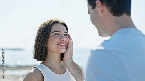 Beautiful couple standing together looking each other touching face at seaside