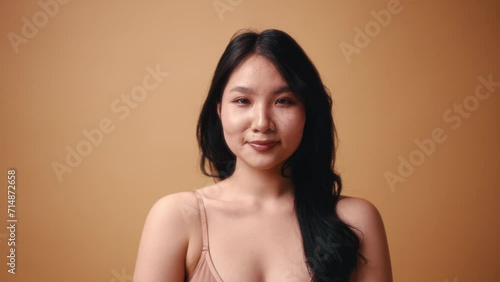 Portrait of a young Asian woman in beige lingerie posing on a beige background. The concept of skin care, cosmetology and spa treatments.