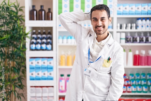 Handsome hispanic man working at pharmacy drugstore smiling confident touching hair with hand up gesture, posing attractive and fashionable © Krakenimages.com