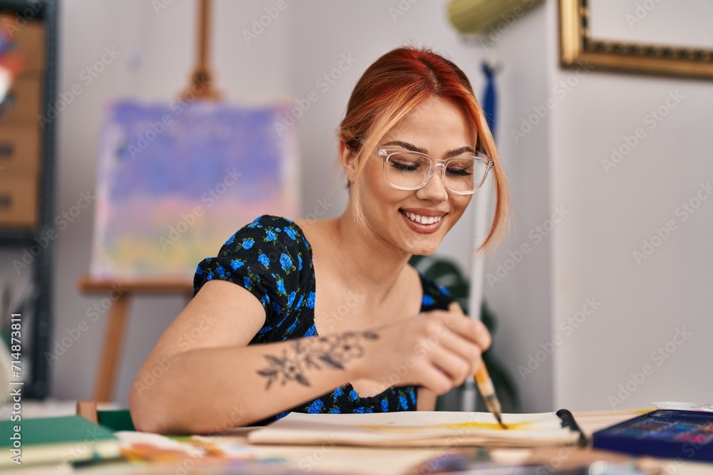 Fototapeta premium Young caucasian woman artist smiling confident drawing on notebook at art studio