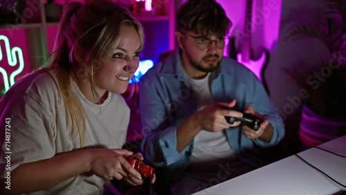 Foto A man and woman enjoy playing video games together in a neon-lit home gaming room at night