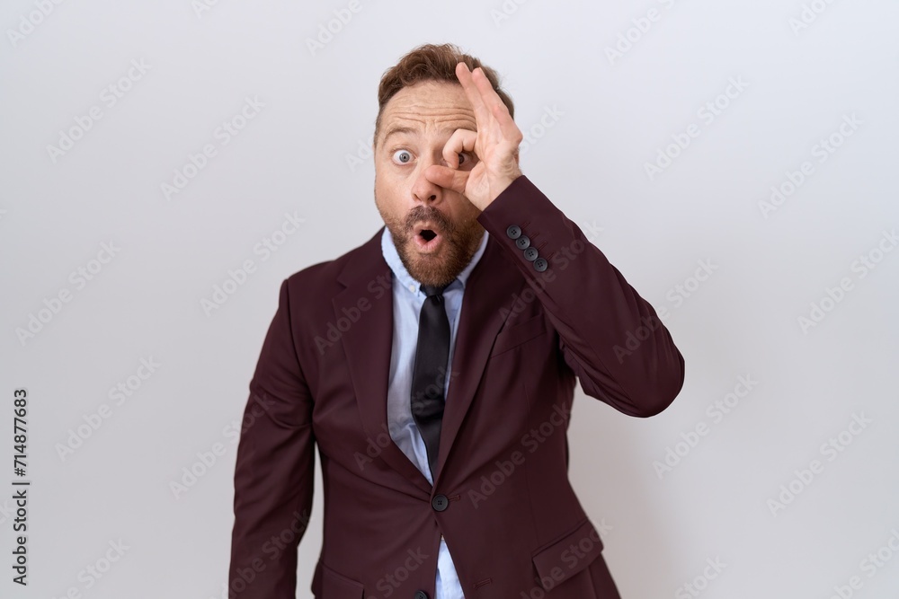 Middle age business man with beard wearing suit and tie doing ok gesture shocked with surprised face, eye looking through fingers. unbelieving expression. Middle age business man with beard wearing suit and tie doing ok gesture shocked with surprised face, eye looking through fingers. unbelieving expression.