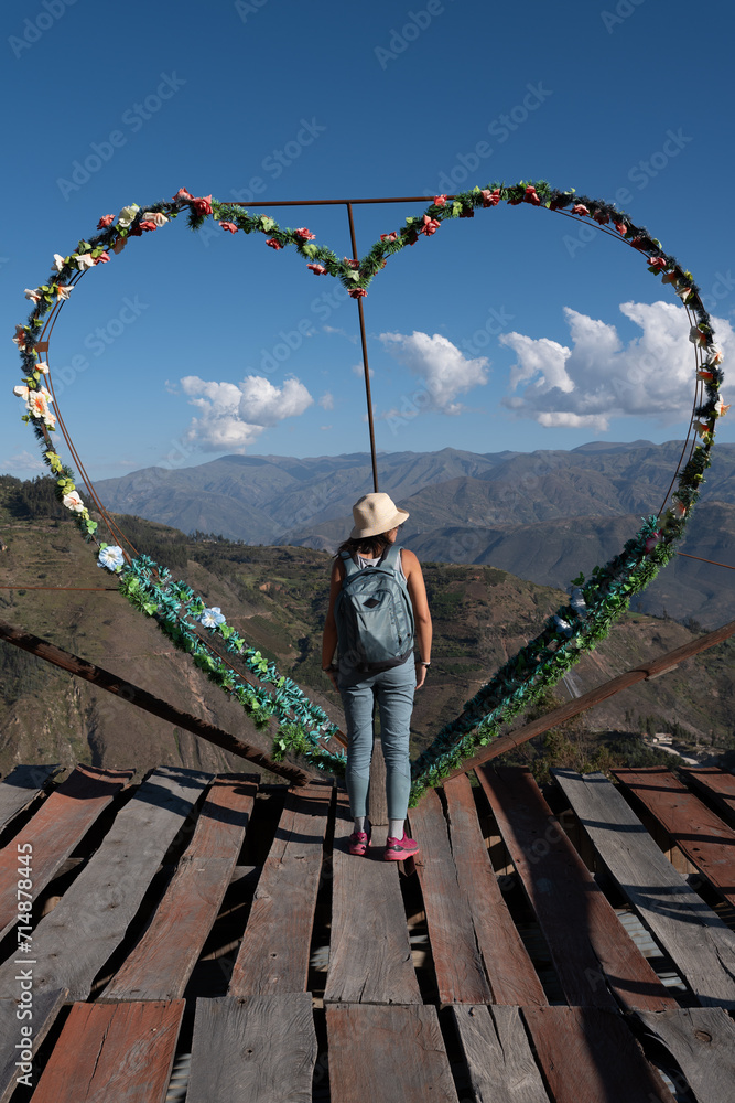 Tourist standing on a viewpoint next to a heart-shaped decoration.
