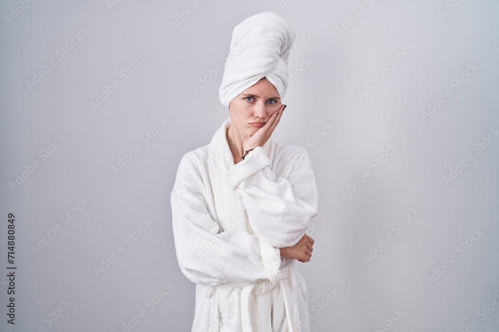 Blonde caucasian woman wearing bathrobe thinking looking tired and bored with depression problems with crossed arms. Blonde caucasian woman wearing bathrobe thinking looking tired and bored with depression problems with crossed arms.