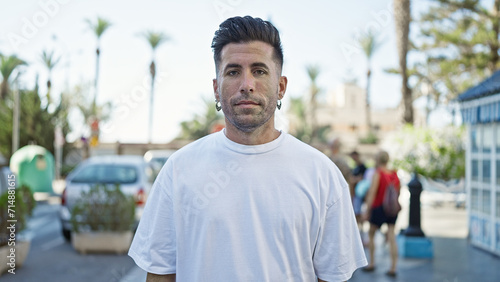 Young hispanic man looking to the camera with serious expression at street