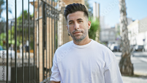 Young hispanic man looking to the camera with serious expression at street