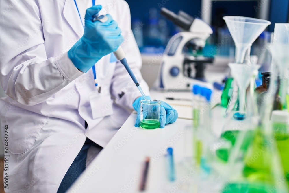 Fototapeta premium Young bald man scientist pouring liquid on test tube at laboratory