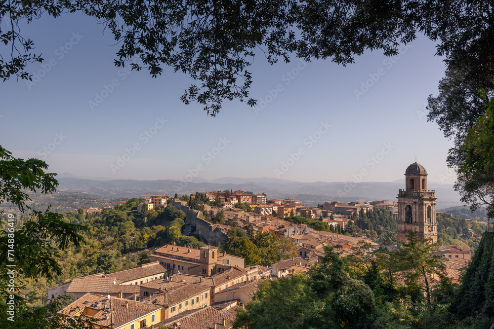 Ancient Italian town on hill with tiled roofs of buildings, church and bell tower, Perugia, Italy