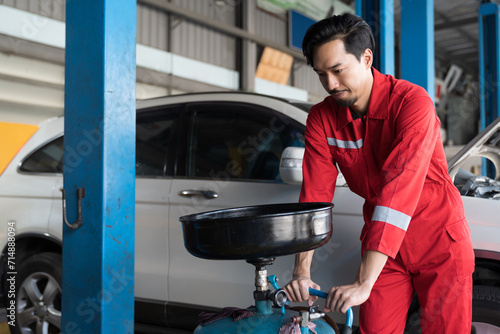 Male mechanic changing engine oil in auto repair shop. Male technician maintenance engine fluid in garage