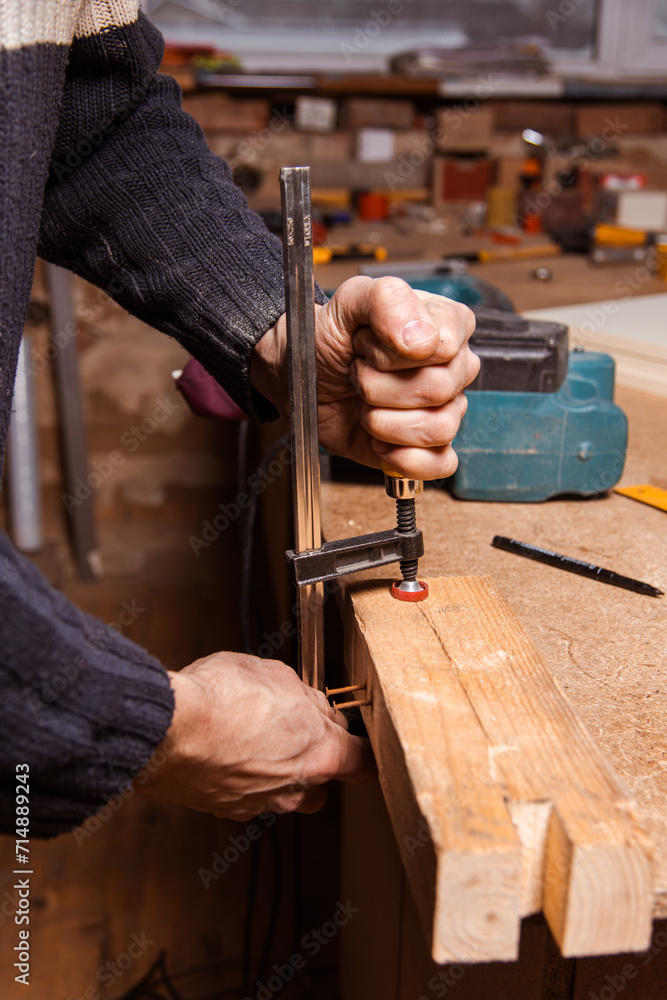 A carpenter works in a furniture workshop with various tools and a board A carpenter works in a furniture workshop with various tools and a board