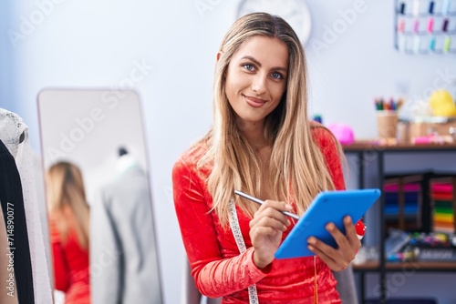Young blonde woman tailor smiling confident drawing on touchpad at tailor shop