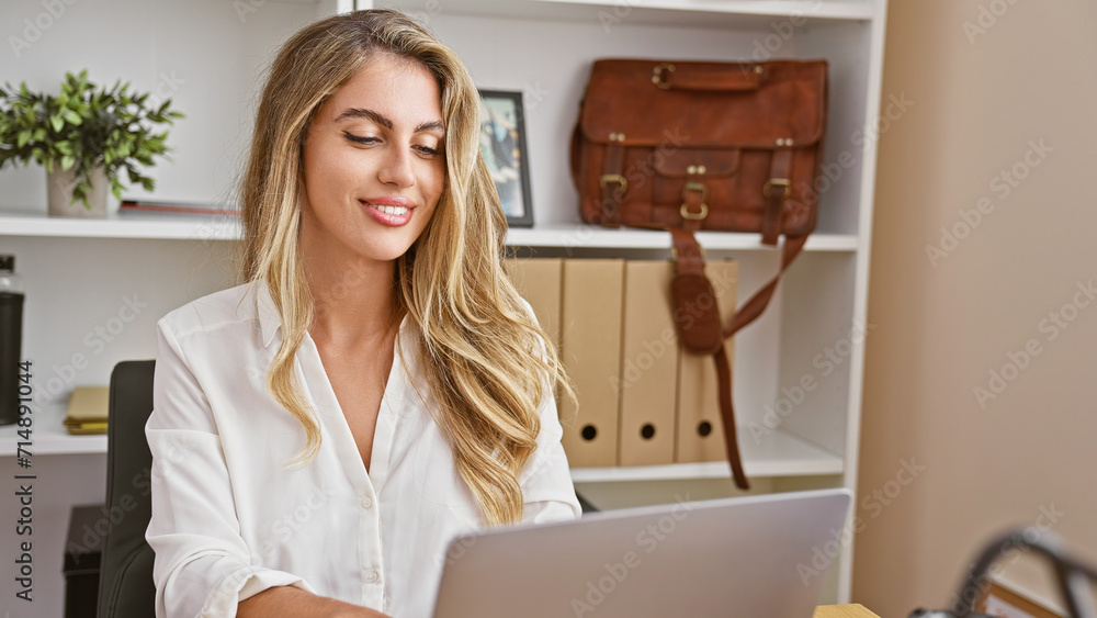 Confident, young blonde business woman brimming with positivity works vibrantly at her office desk, making the computer laptop her tool for professional success, smiling in her elegant indoor room. Confident, young blonde business woman brimming with positivity works vibrantly at her office desk, making the computer laptop her tool for professional success, smiling in her elegant indoor room.