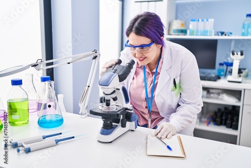 Young beautiful plus size woman scientist using microscope at laboratory
