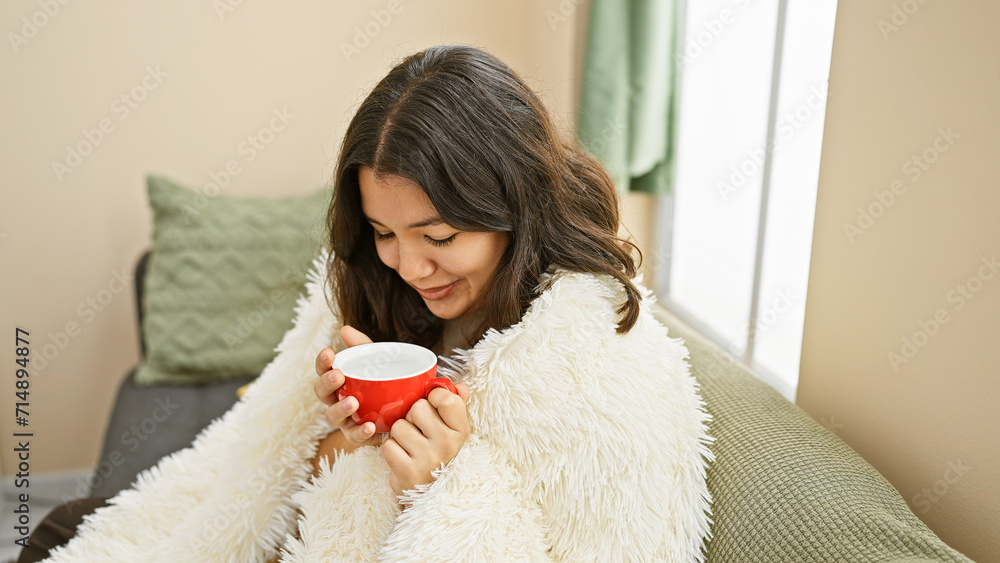 A serene hispanic woman enjoys a warm beverage at home, exuding a cozy and relaxed atmosphere in her living room. A serene hispanic woman enjoys a warm beverage at home, exuding a cozy and relaxed atmosphere in her living room.