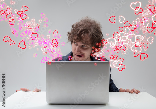 Laptop user chuckles amid a sea of hearts lustily photo