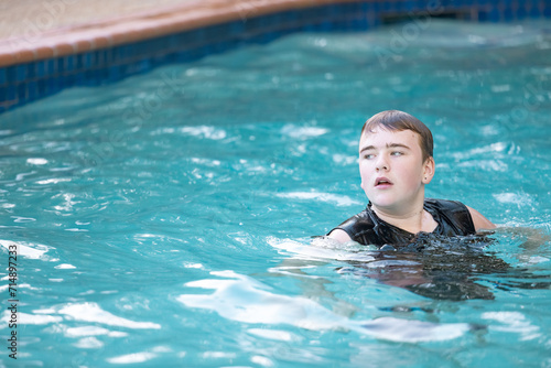 Teen boy swimming in resort pool on vacation