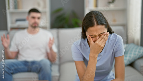 Distressed beautiful couple arguing and crying on the relaxed sofa at home, their love stressed and strained