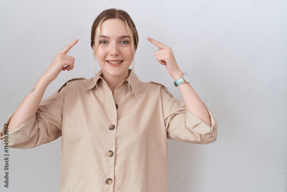 Young caucasian woman wearing casual shirt smiling pointing to head with both hands finger, great idea or thought, good memory Young caucasian woman wearing casual shirt smiling pointing to head with both hands finger, great idea or thought, good memory