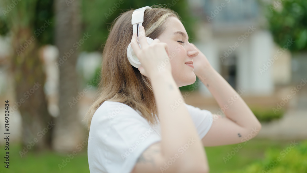 Young caucasian woman listening to music at park