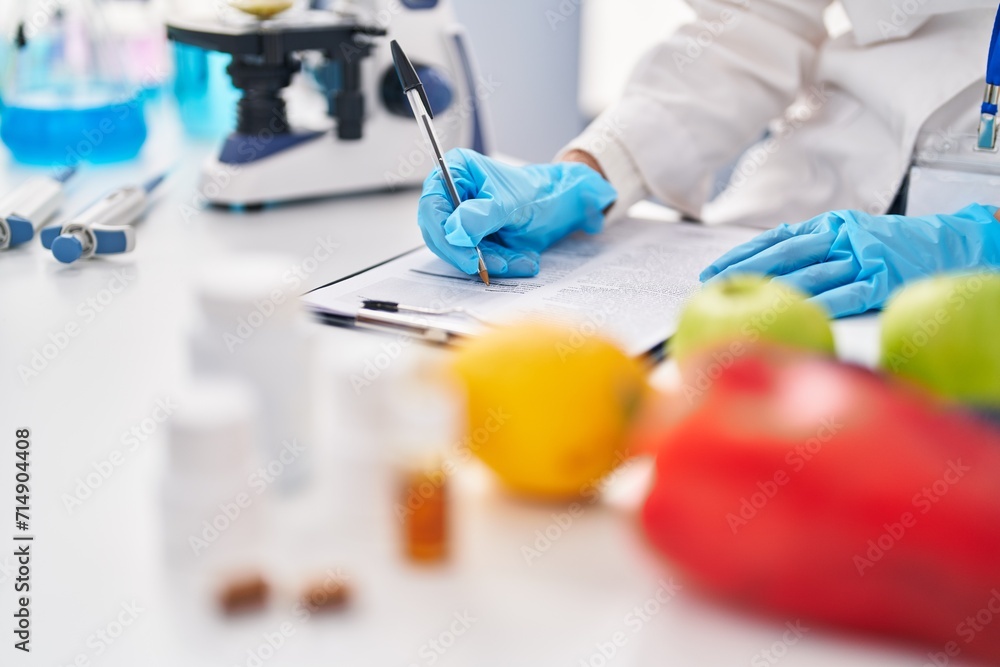 Young beautiful hispanic woman scientist writing food and pills report at laboratory Young beautiful hispanic woman scientist writing food and pills report at laboratory