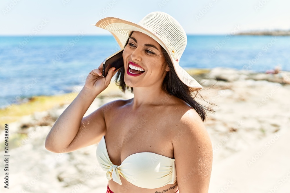 Young beautiful hispanic woman tourist smiling confident talking on smartphone at seaside